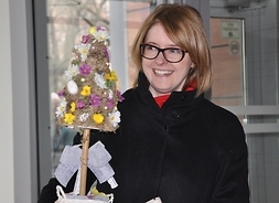 kobieta trzyma w ręku drzewko wykonane z pisanek