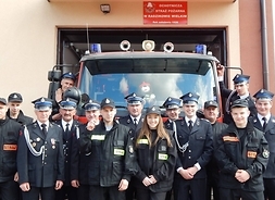 strażacy-ochornicy z Radzikowa Wielkiego stoją w 2 rzędach przed samochodem specjalistycznym