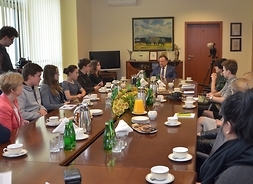 Na zdjęciu widać wielki stół i siedzącą przy nim młodzież oraz marszałka Adama Struzika