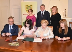 Wicemarszałek Jania Ewa Orzełowska i członek Zarządu Elżbieta Lanc siedzą przy stole, składają podpisy na umowie