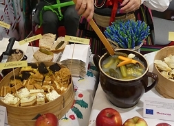 Kobieta w tradycyjnym stroju przygotowuje potrawę. na stole widać półmiski z produktami