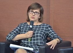 siedzi z mikrofonem zastępca dyrektora Departamentu Budżetu i Finansów ds. Planowania Budżetu Województwa Małgorzata Więckowska
