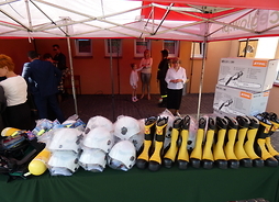 Na stoliku są poukładane hełmy, buty i pilarki dla ochotników z gminy Cegłów
