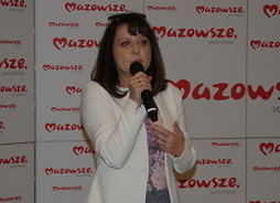 Wicemarszałek Janina Ewa Orzełowska stoi na tle banneru z logo Mazowsza