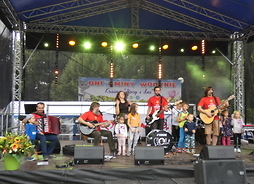 Na scenie występuje zespół „Mała orkiestra dni naszych”. Pomiędzy muzykami stoją dzieci.