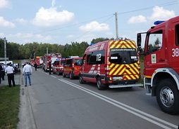 Na ulicy stoją samochody strażackie jednostek uczestniczących w jubileuszu