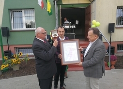 Marszałek Struzik, dyrektor Kominek i przedstawciel ROD prezentują dyplom i medal