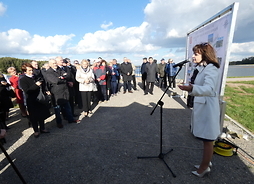 Na zdjęciu Wicemarszałek Jania Ewa Orzełowska stoi i gratuluje inwestycji. Obok widać uczestników prezentacji zbiornika