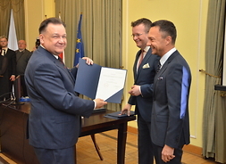 Adam Struzik trzyma w ręku akt potwierdzający złożenie ślubowania na radnego VI kadencji sejmiku województwa mazowieckiego