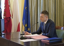 Przy stole przemawia Przewodniczący Sejmiku Województwa Mazowieckiego Ludwik Rakowski. Na stole leżą dokumenty