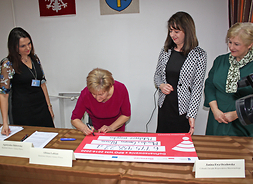 Elżbieta Lanc podpisuje symboliczny czek