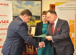 Marszałek przekazuje podpisaną umowę burmistrzowi Skaryszewa Dariuszowi Piątkowi, obaj panowie stoją