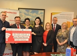 Beneficjenci projektu gminy Ożarów Mazowiecki pozują do zdjęcia z symbolicznym czekiem