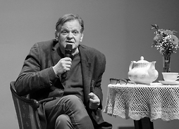jarosław Mikołajewski przy stoliku mówi do mikrofonu, przy nim na stoliku widać stylowy dzbanek z herbatą