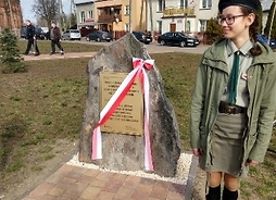 Tablica na Placu Kościelnym, upamiętniająca mieszkańców gminy Sadowne. Po prawej stoi harcerka.