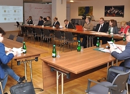 przy stołach ustawionych w kształcie litery U siedzą członkowie Mazowioeckiej Rady Innowacyjności, w tle prezentacja na temat celów zrównoważonego rozowju regionu
