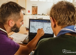 Dwóch uczestników rajdu przegląda  na monitorze komputera mapę topograficzną
