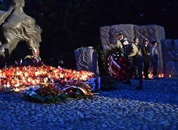 Cmentarz Powstańców Warszawskich na Woli, wieczór, pod pomnikiem palące się znicze