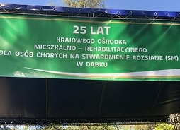 na zielonym tle widac napis 25 lat działalności KOMR w Dąbku