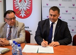 Siedząc za stołem, umowę podpisują przedstawiciele władz miasta i gminy Drobin, burmistrz i skarbnik.