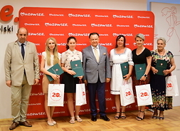 przed banerem z logo Mazowsza stoją wspólnie laureaci konkursu oraz przedstawiciele samorządu Mazowsza