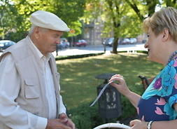 Elżbieta Lanc częstuje jabłkiem starszego mężczyznę