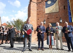 Marszałek Adam Struzik oraz inni goście pozujący do zdjęcia przed zegarem słonecznym