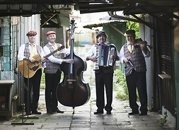 pięciu męzczyzn z instrumentami stoi na chodniku