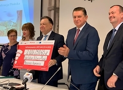 Przedstzwiciele samorzadu Mazowsza oraz beneficjenci z Płońska trzymają w rękach symboliczny czek. Projekty otrzymają łącznie ponad 8,2 mln zł dofinansowania w ramach Regionalnego Programu Operacyjnego Województwa Mazowieckiego 2014–2020