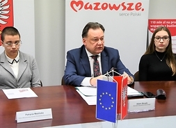 Mówi marszałek Adam Struzik, obok radne Młodzieżowego Sejmiku Województwa Mazowieckiego Patrycja Mezińska (po lewej) i Julia Liszewska. Siedzą za stołem prezydialnym.