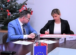 wójt gminy Wiskitki Rafał Mitura oraz skarbnik gminy Wiskitki Danuta Taras siedzą za stołem i podpisują tablicę z czekiem.