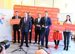 Za mikrofonami stoją marszałek Adam Struzik i prezydent Warszawy Rafał Trzaskowski, obok trzy osoby z tablizami "Nie dla podziału Mazowsza", za nimi jeszcze dwóch uczestników konferencji.