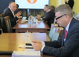 Kilkoro radnych siedzi na sali obrad za stołami, na pierwszym planie radny Mirosław Augustyniak.