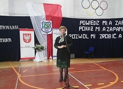 Przed mikrofonem stoi członek zarządu Elżbieta Lanc. W tle baner z herbem Mazowsza i flaga Polski