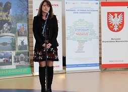 Członek zarządu Janina Ewa Orzełowska stoi przed mikrofonem