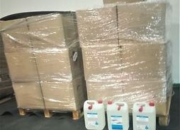 Paczki na paletach i trzy pojemniki z płynem dezynfekującym luzem - zestaw kilkunastu paczek wyposażenia przygotowany do przewiezienia do szpitala.