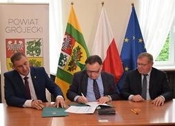 Za stołem siedzą: po środku Adam Struzik, który podpisuje umowę, po lewej starosta powiatu grójeckiego Krzysztof Ambroziak, po prawej radny województwa mazowieckiego Leszek Przybytniak.
