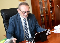 Na fotelu przy stole, wpatrzony w ekran laptopa, siedzi Marek Miesztalski, Skarbnik Województwa Mazowieckiego.