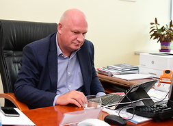 Na fotelu przy stole, wpatrzony w ekran laptopa, siedzi radny Paweł Jerzy Obermeyer.