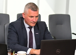 Na fotelu przy stole, wpatrzony w ekran laptopa, siedzi Rafał Rajkowski, wicemarszałek Województwa Mazowieckiego.