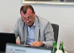 Na fotelu przy stole, wpatrzony w ekran laptopa, siedzi Wiesław Raboszuk, wicemarszałek Województwa Mazowieckiego.
