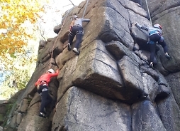 Trzy osoby wspinają się na skałę