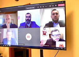 Widok ekranu monitora podczas zdalnego spotkania. Ekran podzielony jest na sześć kwadratów, na których pojawiają się osoby uczestniczące w spotkaniu online.