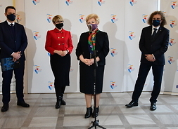 konferencja prasowa, na tle banera stoją cztery osoby, dwie kobiety i dwóch mężczyzn,wszyscy mają maseczki na twarzy