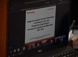 Zdjęcie otwartego laptopa, na którym wyświetla się prezentacja ze spotkania online.
