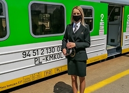 Kobieta w mundurze na peronie, w tle pociąg