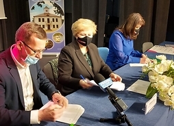 Mężczyzna i dwie kobiety podpisują dokumenty