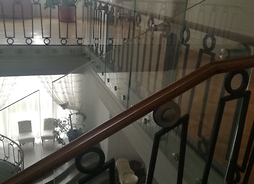 Widok na balustradę schodową, a nad nią tafle szkła podwyższające balustrady o 30 cm
