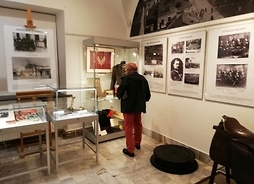 Jeden ze zwiedzających przygląda się archiwalnym zdjęciom, zamieszczonym w galerii