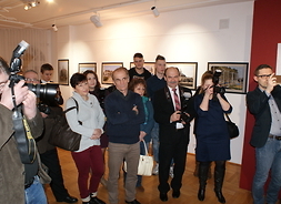 powiększ zdjęcie, goście muzeum słuchają prezentacji artysty, część z nich robi zdjęcia